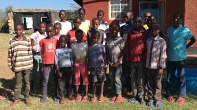 20 Kinder stehen vor dem Waisenhaus Beat the Drum