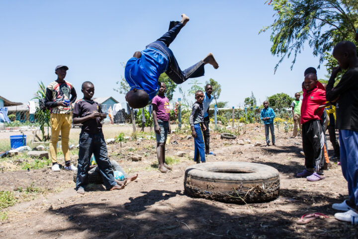 Kenianischer Junge macht einen Salto von einem alten Lastwagenpneu