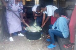 Die Köchin zeigt den Kindern, wie die traditionelle Speise Mukimo (Kartoffelstock) zubereitet wird.
