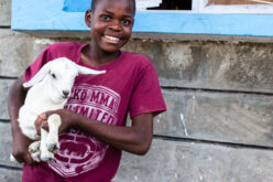 Strahlendes Kind mit Ziege auf dem Arm