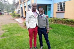 Ein kenianischer Mann mit weissem Jacket und roter Hose steht links. Recht steht ein kenianischer Jugendlicher in Schuluniform (grauer Pullover, dunkelblaue Hose). Die beiden haben sich die Arme um die Schulter gelegt