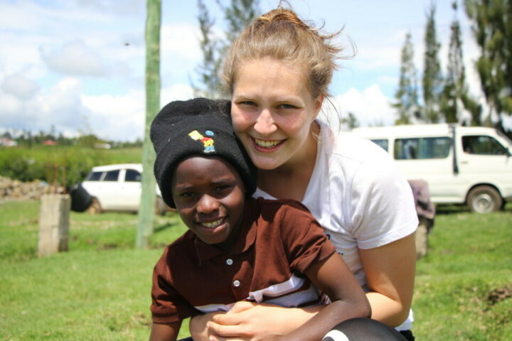 Schweizer Volontärin hält kenianisches Kind mit schwarzer Mütze