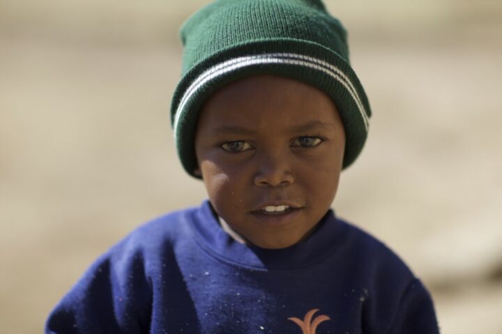 Kenianisches Kind mit grüner Mütze und blauem Pullover